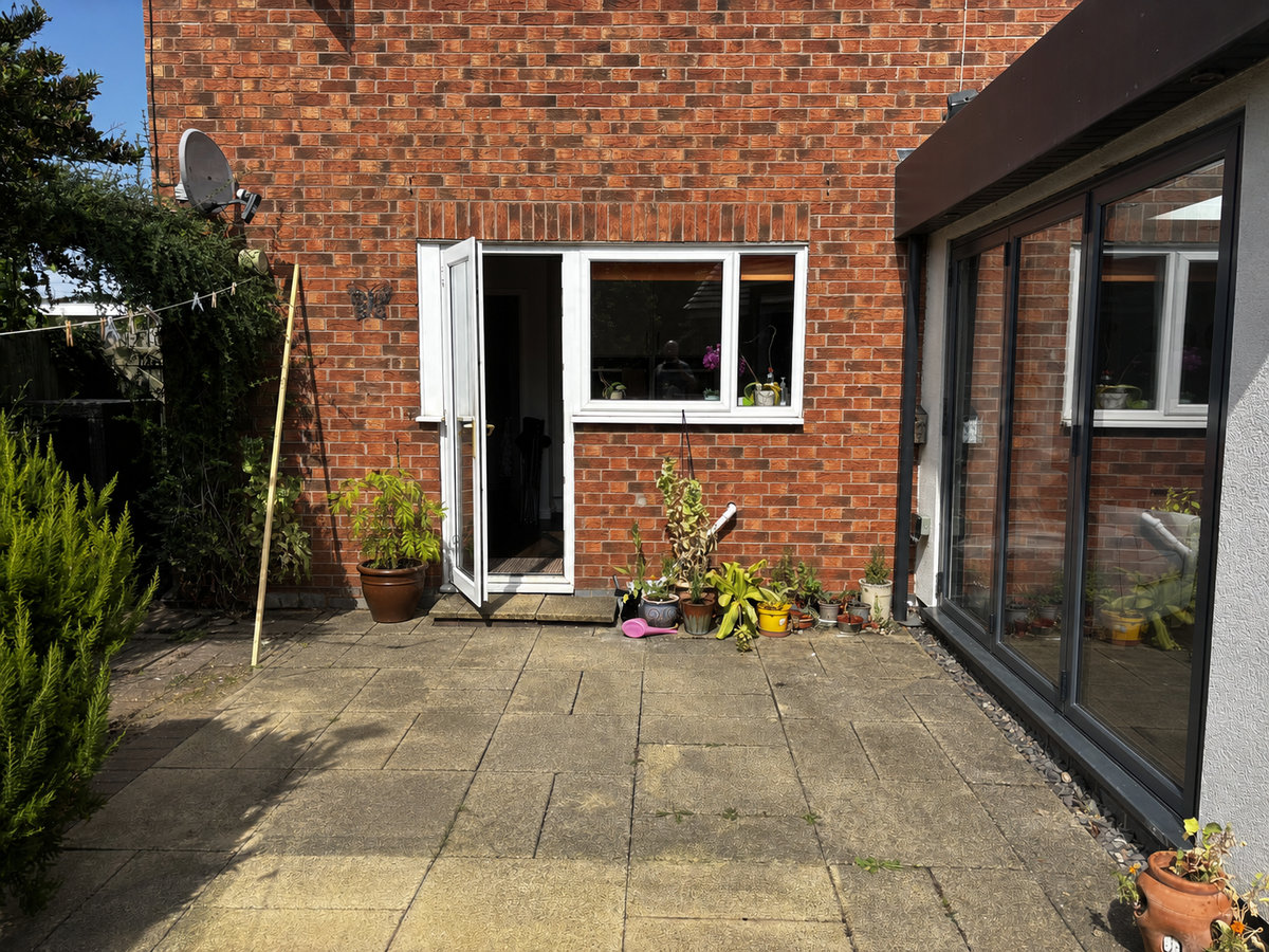 S01 house terrace photographed in daylight, with two movable chairs removed and the black-framed orangery door shown closed